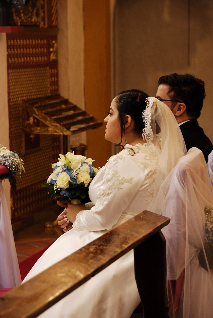 La sposa con il bouquet accanto allo sposo davanti all'altare