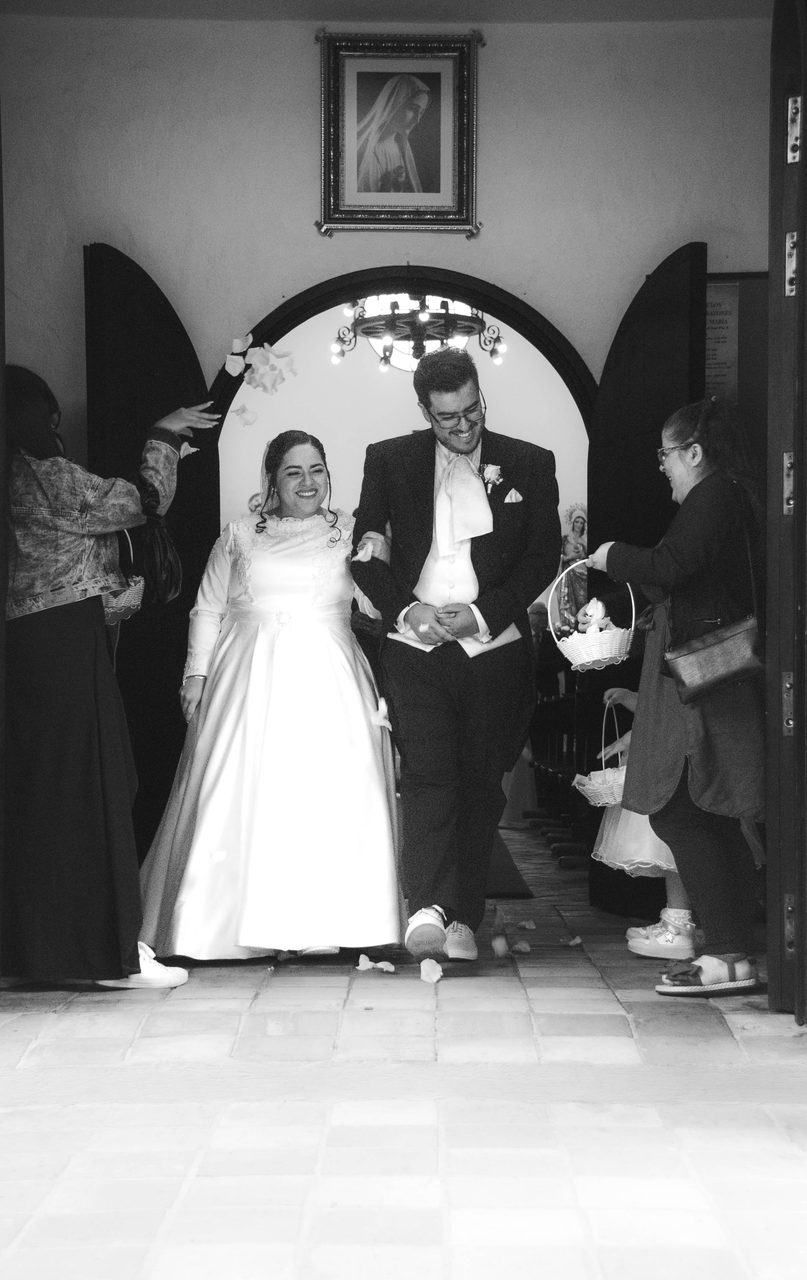 Gli sposi escono dalla chiesa tra i petali, in bianco e nero